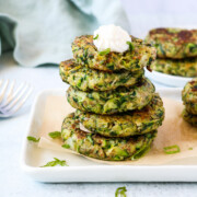 zucchini fritters on a plate with vegan sour cream.